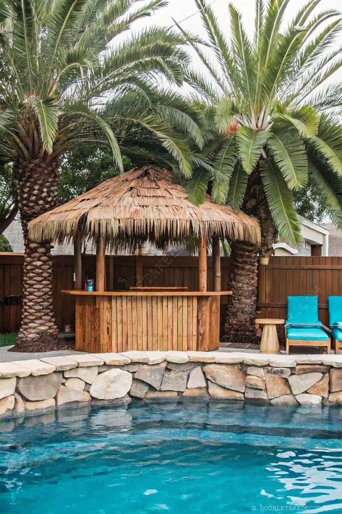 A backyard swimming pool with a thatched-roof tiki bar, turquoise chairs, and palm trees creating a tropical paradise retreat.