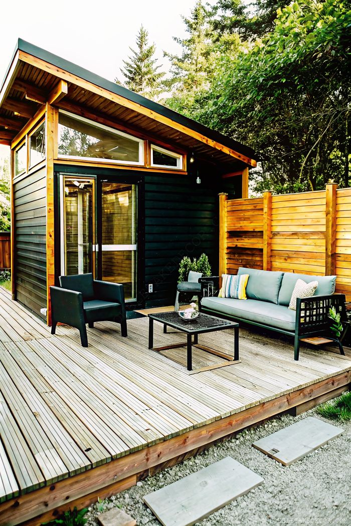 Modern outdoor living space with wooden privacy fence surrounding a stylish cabin deck with comfortable seating.