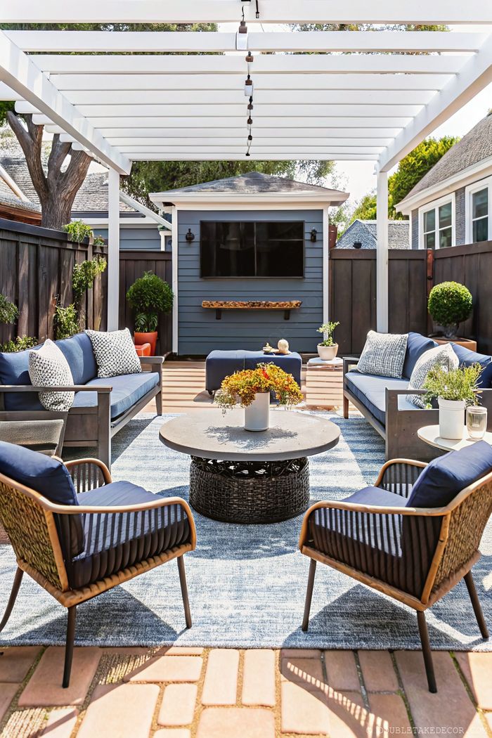 Elegant outdoor living space with white pergola, blue furniture, and string lights offering perfect backyard privacy.