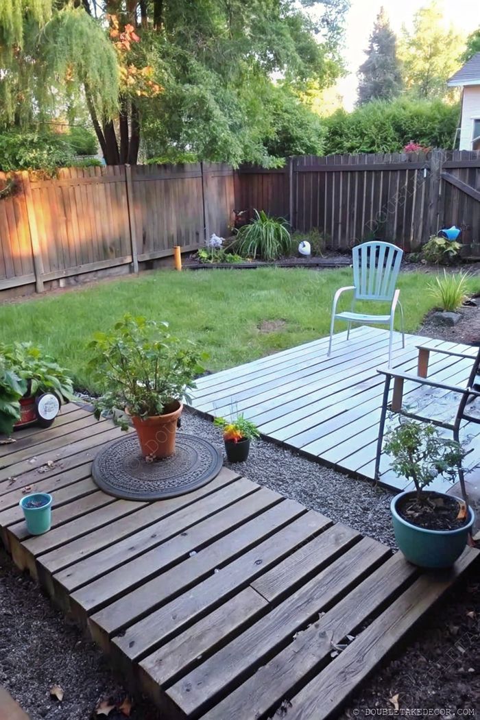 Petite terrasse en palettes avec plantes en pots, chaise en métal et vue ensoleillée sur le jardin, idéale pour se détendre dehors.