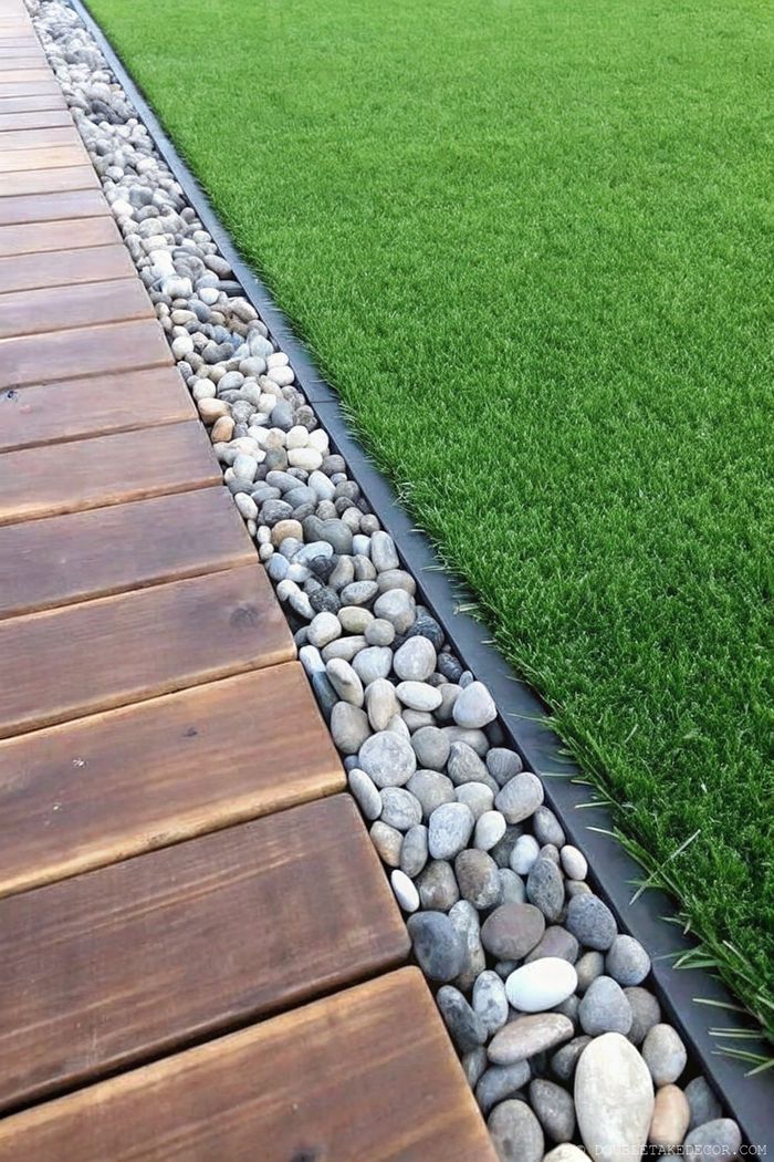 Stilvoller Holzsteg mit Kies-Einfassung, der sanft in einen Kunstrasen übergeht und einen praktischen Gartenbereich bildet