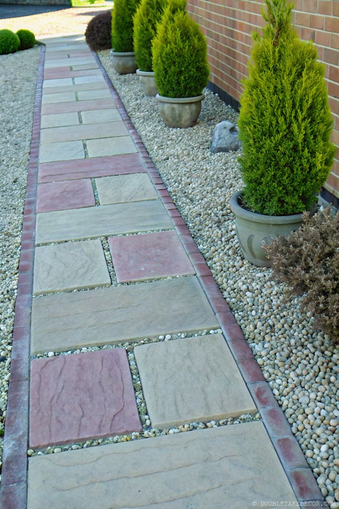 Gartenweg mit geometrischem Muster, Abgrenzung aus roten Ziegeln, dekorativen Pflanztöpfen und Kiesflächen.