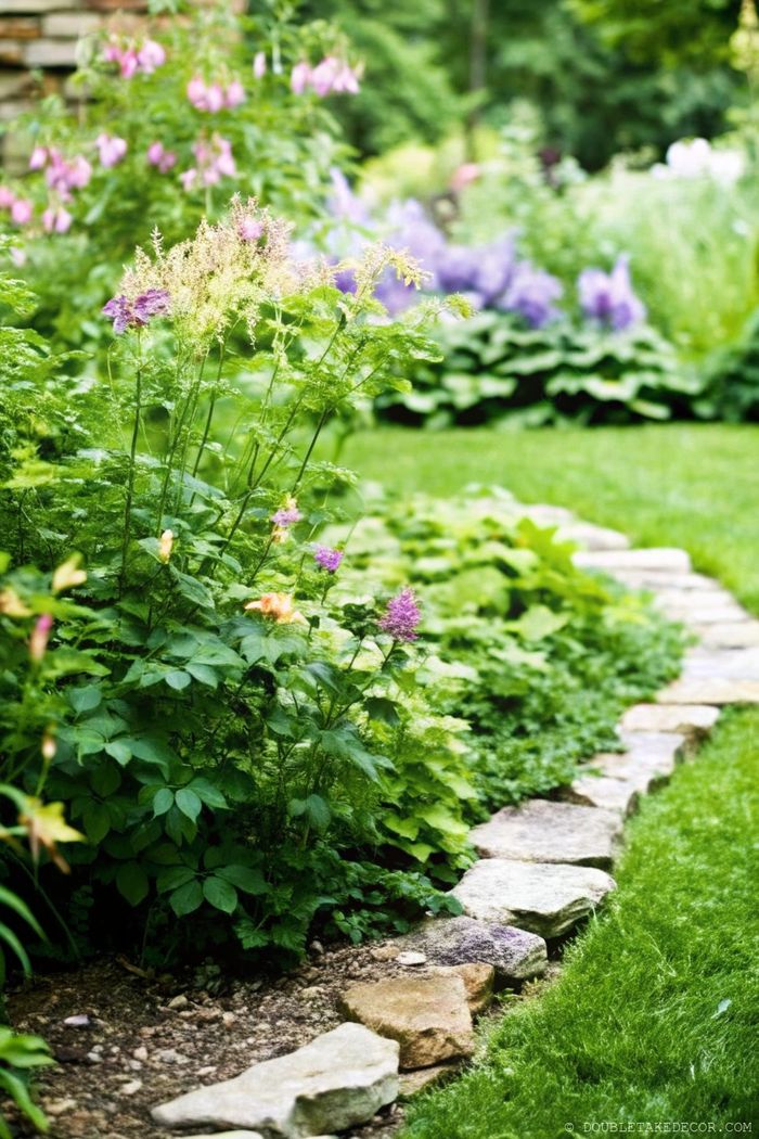 Lebendiger Garten mit violetten und gelben Blumen, die von einem unregelmäßigen Steinweg begrenzt werden. Das ergibt eine gelungene Mischung aus Funktionalität und Design.