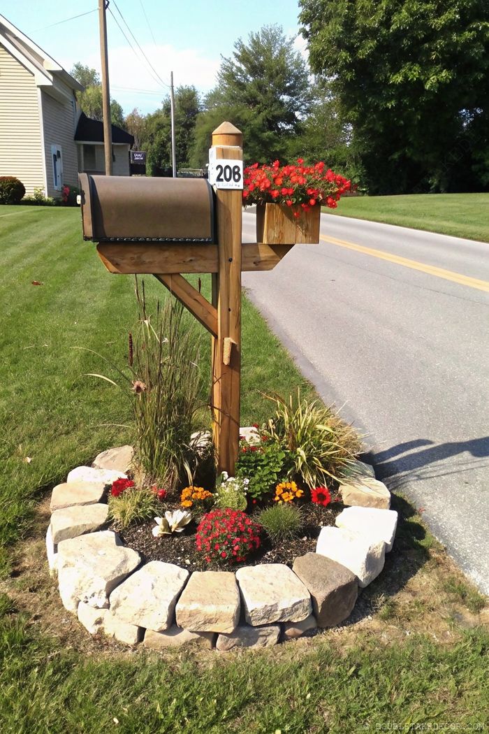Charming rustic mailbox with wooden planter of red flowers, surrounded by stone-bordered circular garden of colorful blooms.