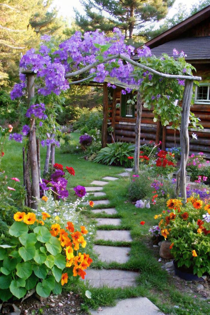 Stone garden path with colorful flowers leading to a rustic log cabin, crowned by a wooden arch with purple blooms