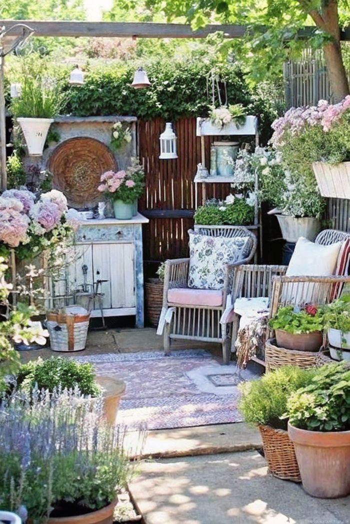 Rustic garden with wicker chairs, distressed table, hydrangeas and decorative shelving creating a charming shabby chic retreat.