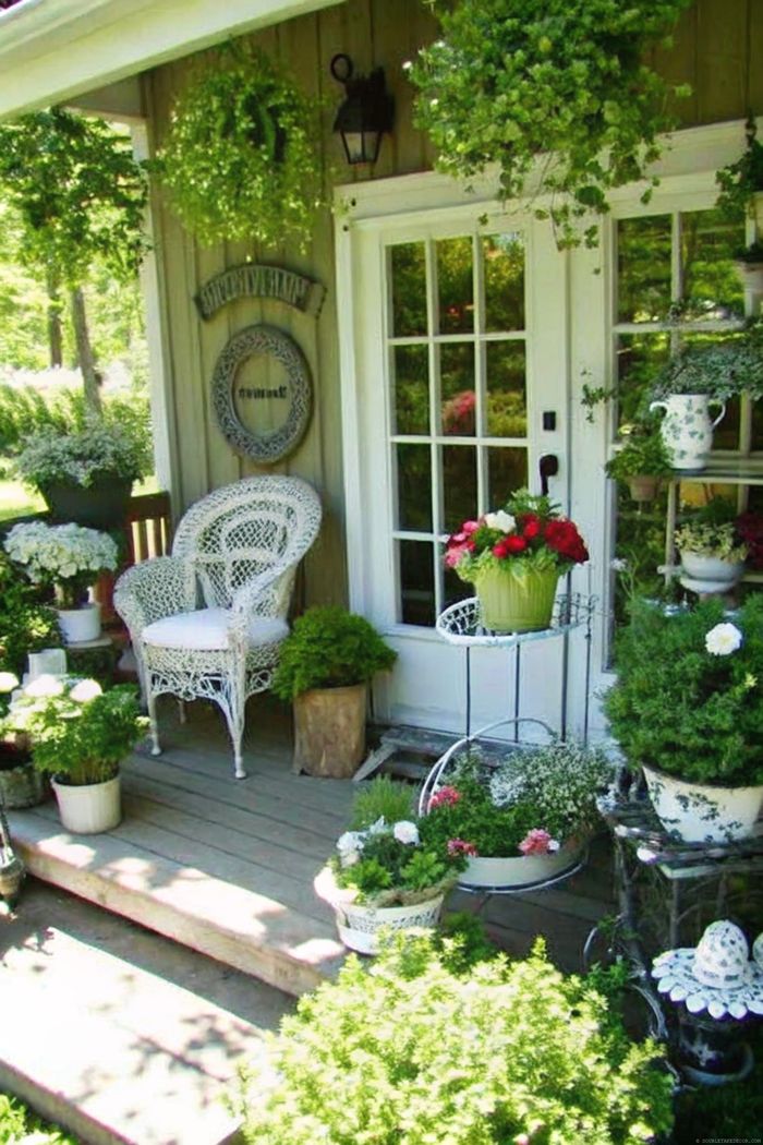 Charming outdoor space with white wicker chair, vibrant potted plants, and hanging greenery creating a serene shabby chic garden retreat
