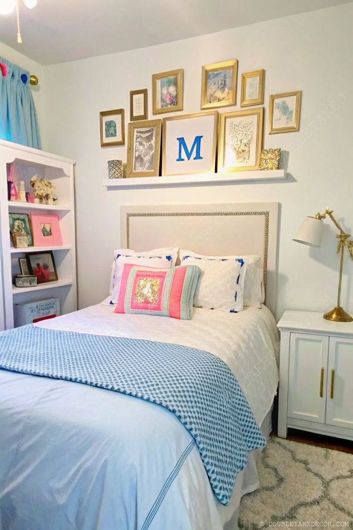 Cozy dorm room with white bedding, blue blanket, colorful pillows, and personalized wall art including a decorative 