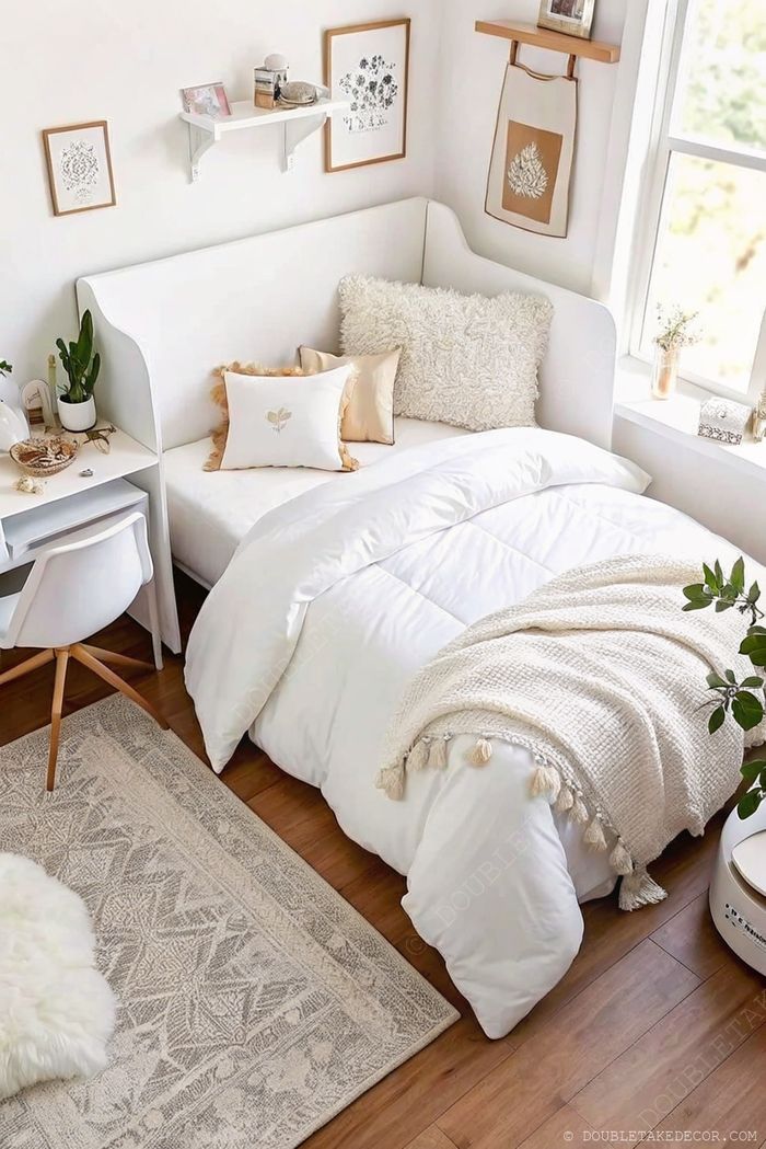 Cozy minimalist bedroom featuring white bedding, wooden floors, compact desk space, and natural light from a large window.