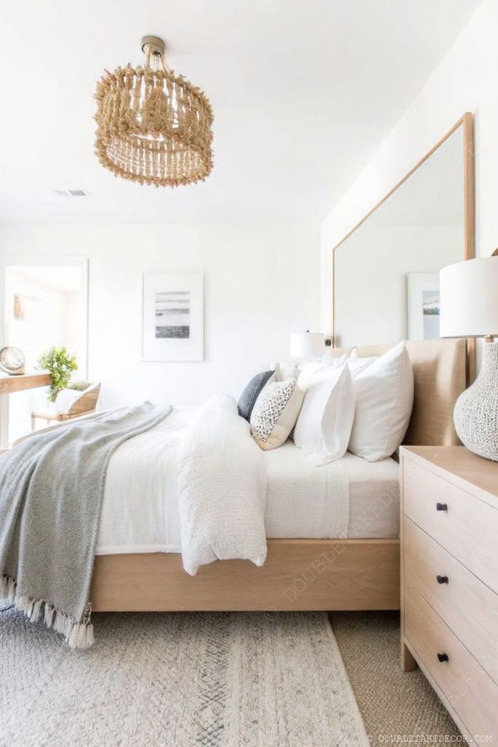 Cozy dorm room with layered bedding, woven light fixture, wooden nightstand, and minimalist workspace creating a serene aesthetic.