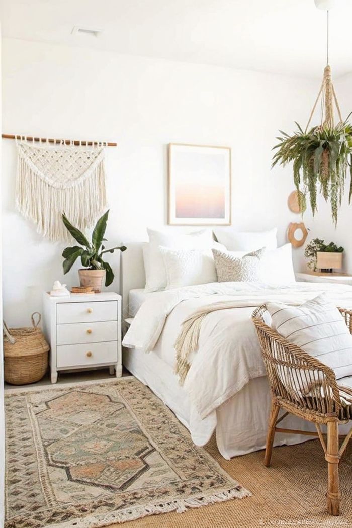 Bright dorm room with white bedding, macramé wall hanging, woven basket, and rattan chair creating a modern boho aesthetic.