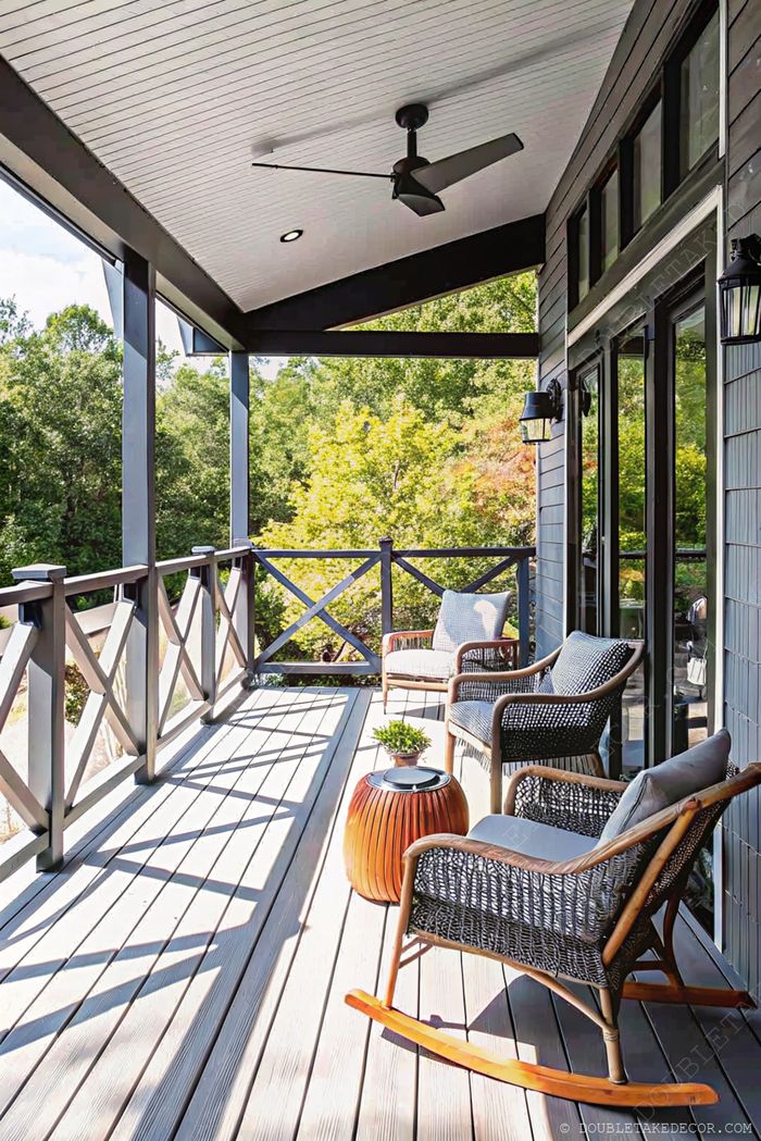 Spacious porch with light composite deck, white beadboard ceiling, woven armchairs, and wooden rocking chair overlooking greenery.