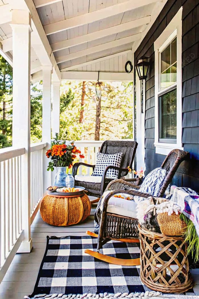 Cozy wicker rocking chairs on black and white checkered rug with woven basket table, flowers, and navy blue walls creating a serene retreat