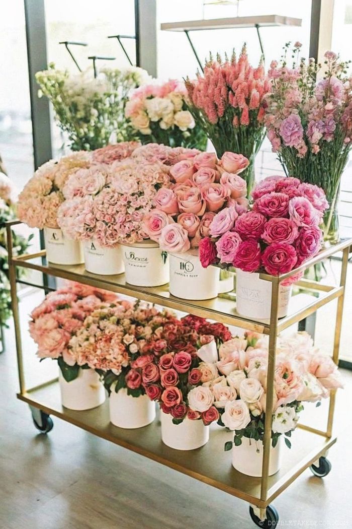 Beautifully arranged pink flowers in white pots on a gold cart, creating an elegant display perfect for DIY flower bar inspiration.