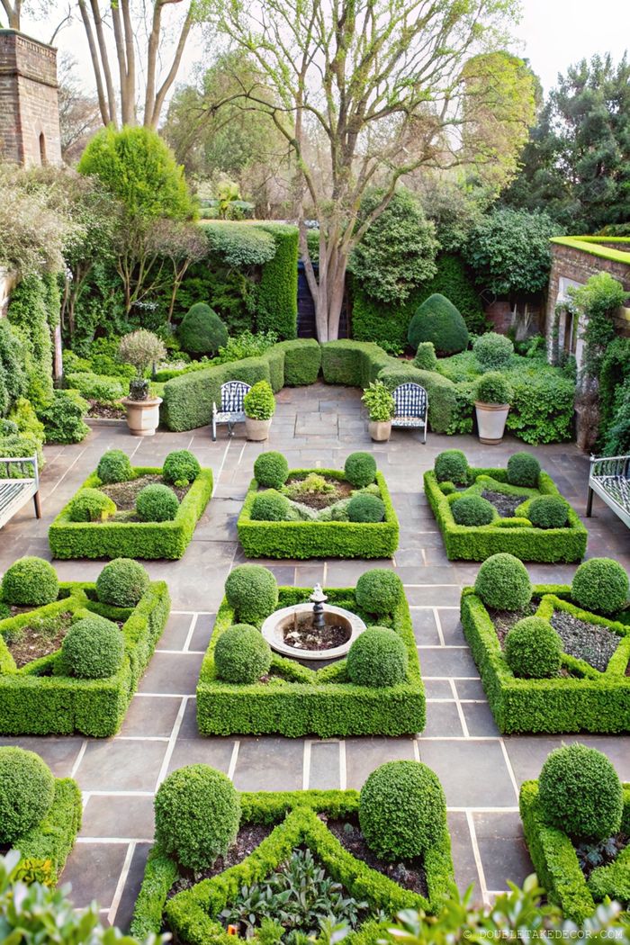 Formal French garden featuring symmetrical hedges, topiary, and a central fountain with elegant black and white patterned seating.