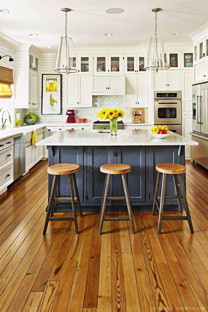 Bright kitchen with white cabinetry, gray island with marble countertop, and three wooden bar stools for casual dining.