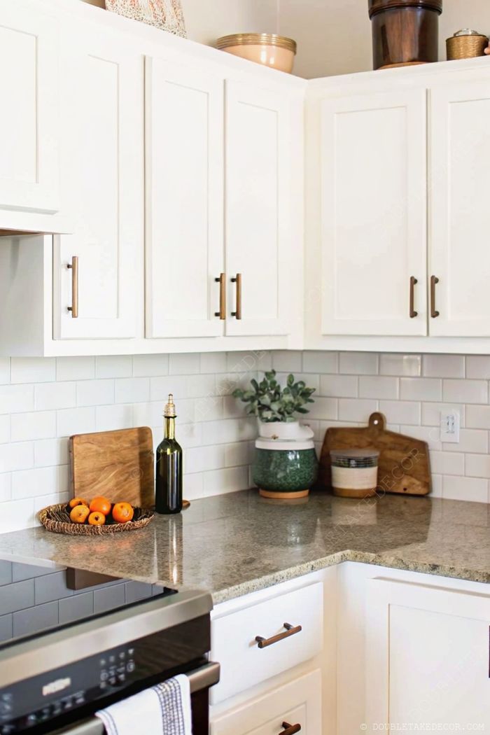 Stylish kitchen corner with white cabinets, granite countertop, basket of oranges, olive oil bottle and wooden cutting boards
