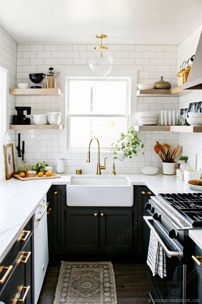 Modern kitchen with farmhouse sink, gold faucet, open shelving, and decorative elements including fresh oranges and potted plant.