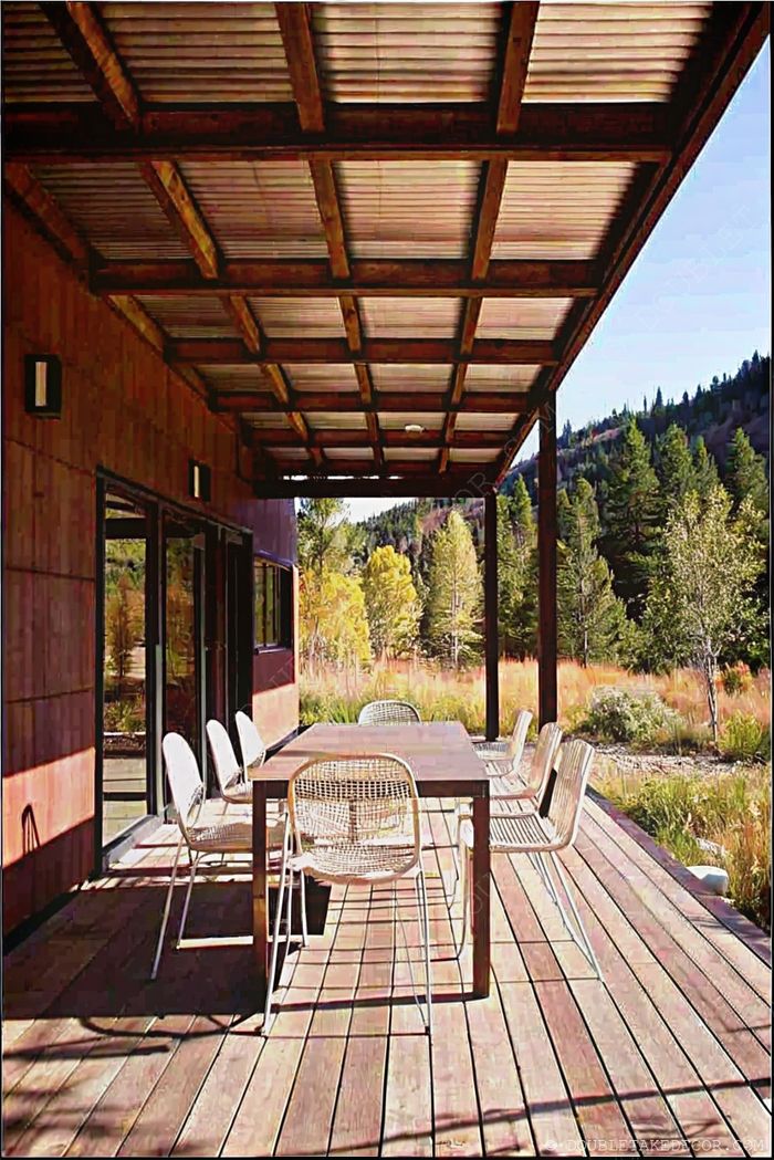 Spacious wooden deck with modern slatted roof covering a dining area, surrounded by natural landscape