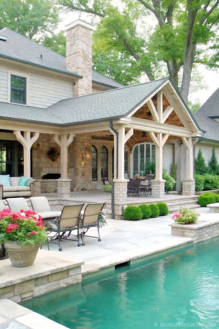 Rustic covered patio with wooden beams, comfortable seating, adjacent dining area, and pool surrounded by lush greenery.