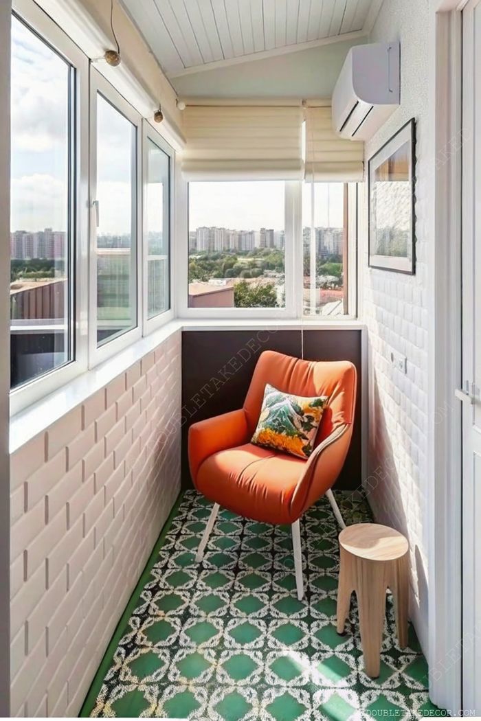Cozy modern balcony featuring large windows, an orange armchair with decorative cushion, wooden stool, and patterned green and white tiles