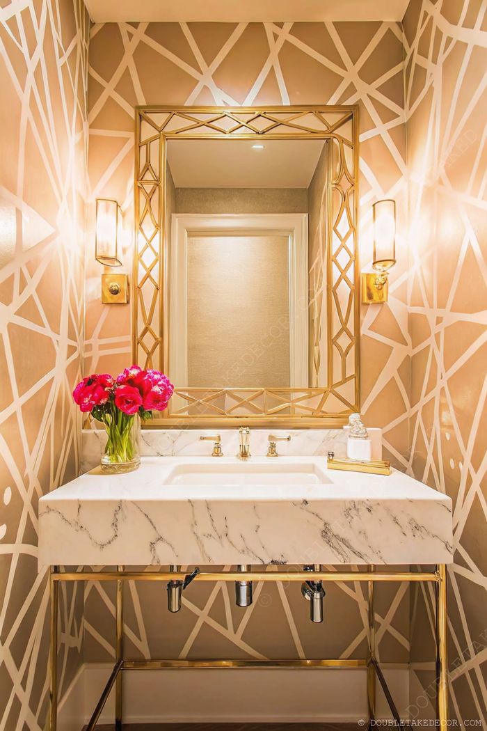 Petit espace moderne avec murs à motifs géométriques, miroir doré, plan de travail en marbre et touches florales roses pour une ambiance élégante.