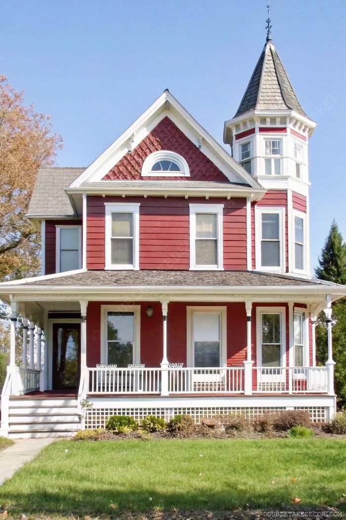 Stunning Victorian-style home with red siding, white trim, and an inviting wraparound porch supported by elegant columns.