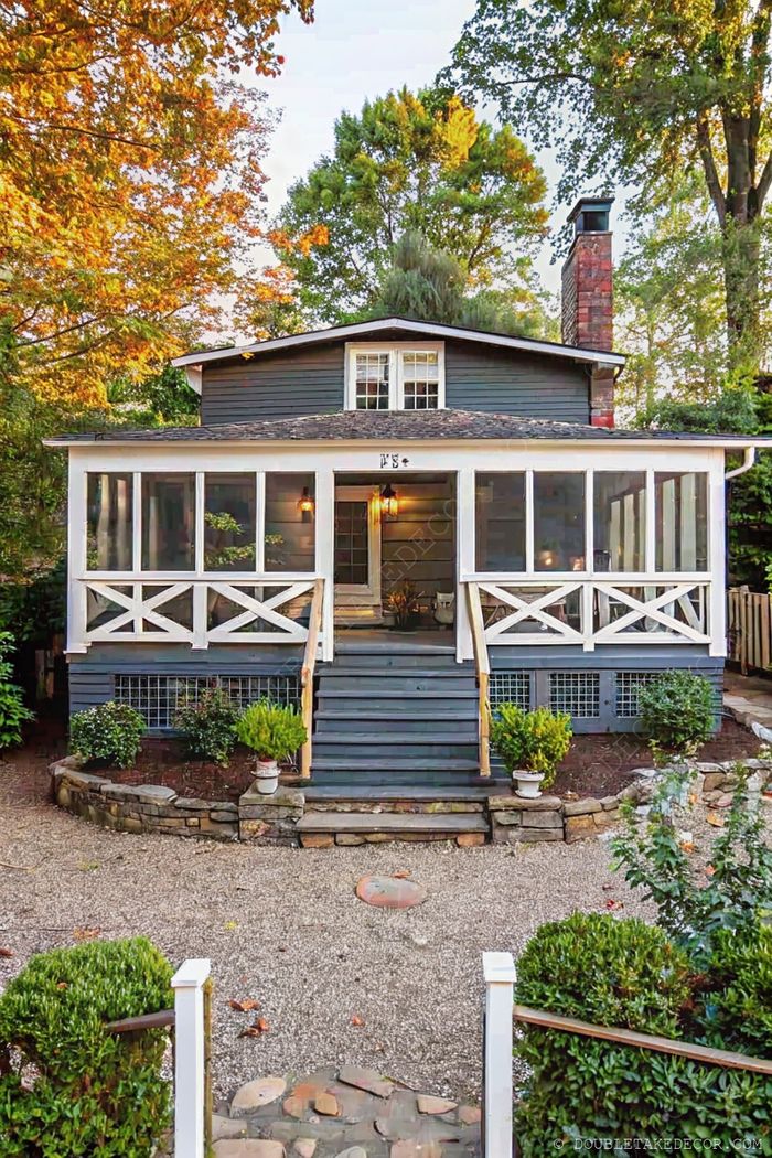 Charming blue-gray house with white trim featuring a screened-in front porch, wooden steps, and tasteful landscaping