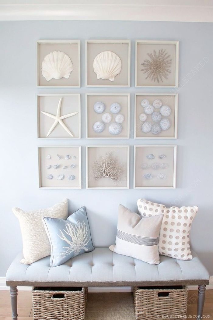 Framed sea-themed artwork on blue wall with tufted bench below featuring coastal-patterned pillows and wicker storage baskets