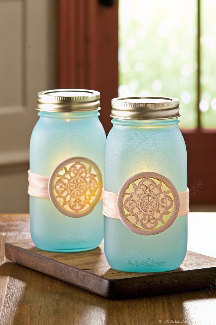 DIY nautical decor: Blue-tinted mason jar lights with circular cut-outs, creating a warm coastal glow on a wooden tray