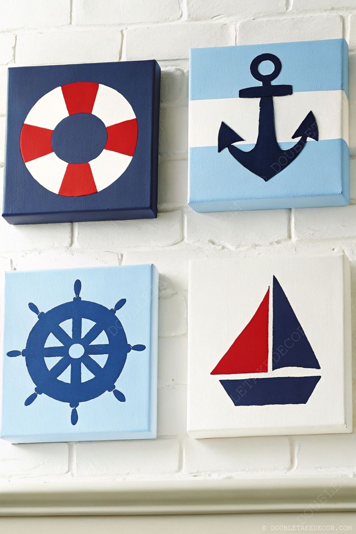 Four nautical-themed canvases featuring a life preserver, anchor, ship's wheel, and sailboat in red, white, and blue colors on a white brick wall.