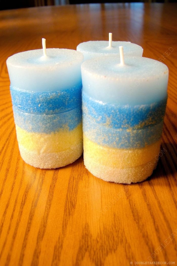 Three decorative candles with gradient layers from light blue to vibrant blue and yellow, arranged on a wooden surface for nautical-themed home decor.