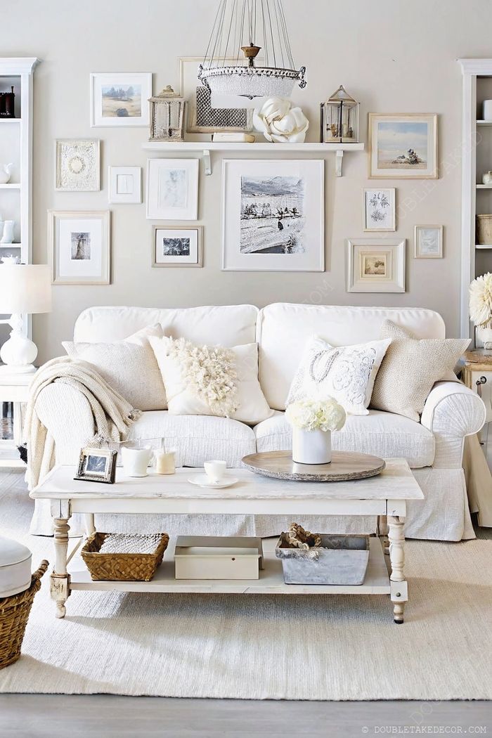 Kényelmes fehér kanapé díszpárnákkal, galériafal, puha dekorral. Nyugodt shabby chic nappali.