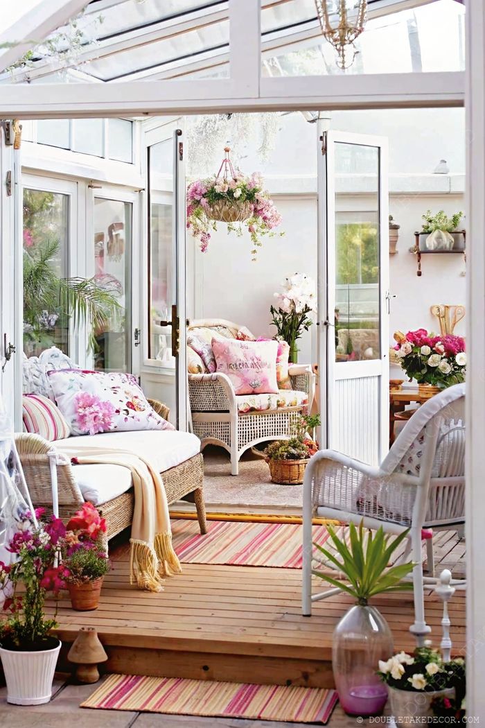 Barátságos télikert fonott bútorokkal, virágos párnákkal, cserepes növényekkel és sok természetes fénnyel–nyugodt shabby chic atmoszféra.