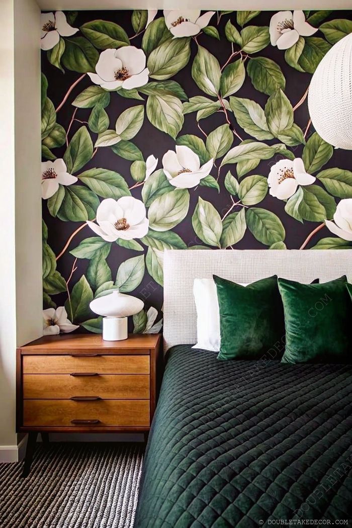 Sophisticated bedroom with dark magnolia wallpaper, plush green bedding, wooden nightstand, and textured rug creating a nature-inspired sanctuary.