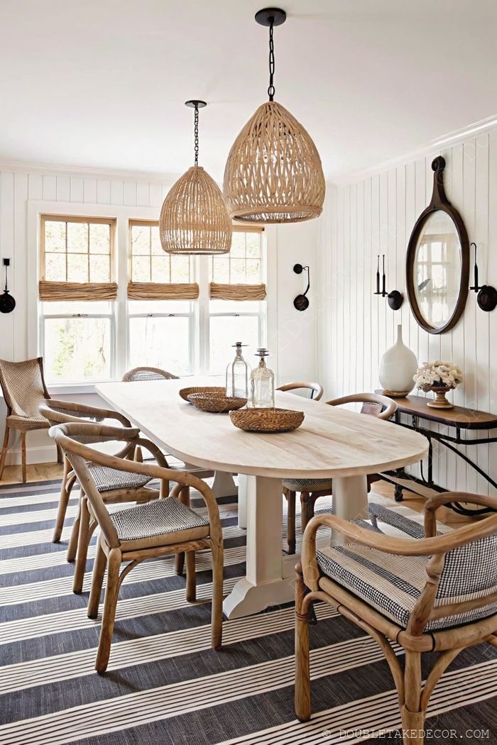 Cozy dining room featuring oval wooden farmhouse table, modern chairs, and woven rattan pendant lights above white shiplap walls.