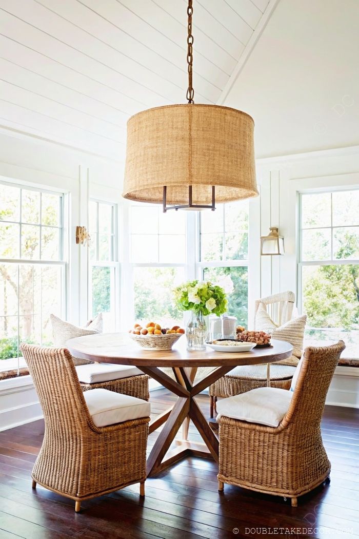 Bright dining space featuring a round wooden farmhouse table with woven chairs and burlap pendant light, perfect for gatherings.
