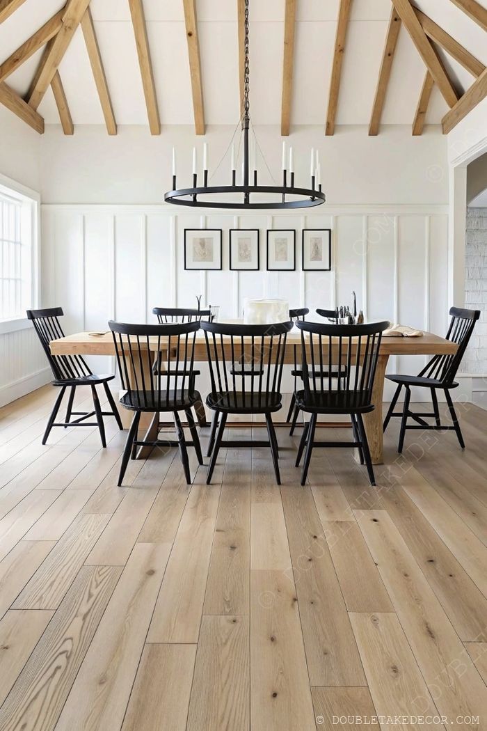 Rustic wooden dining table with black spindle chairs beneath a round chandelier and exposed ceiling beams, creating perfect farmhouse charm.