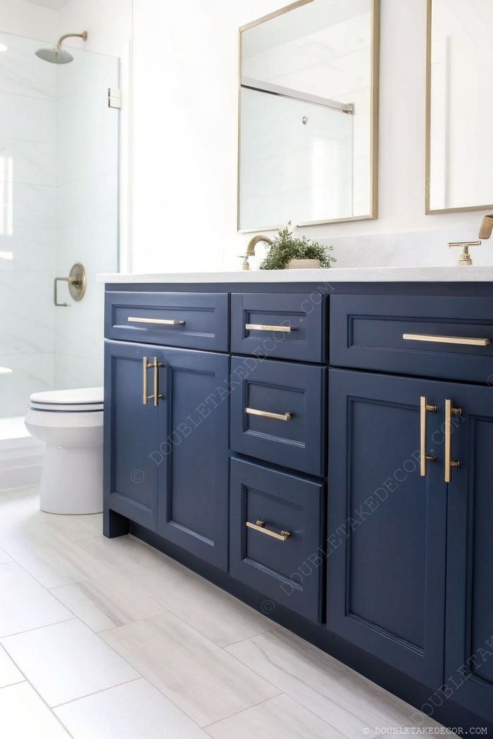 Modernes Bad mit navyblauem Waschtisch und goldenen Griffen, dazu Steinplatte und elegante Spiegel.