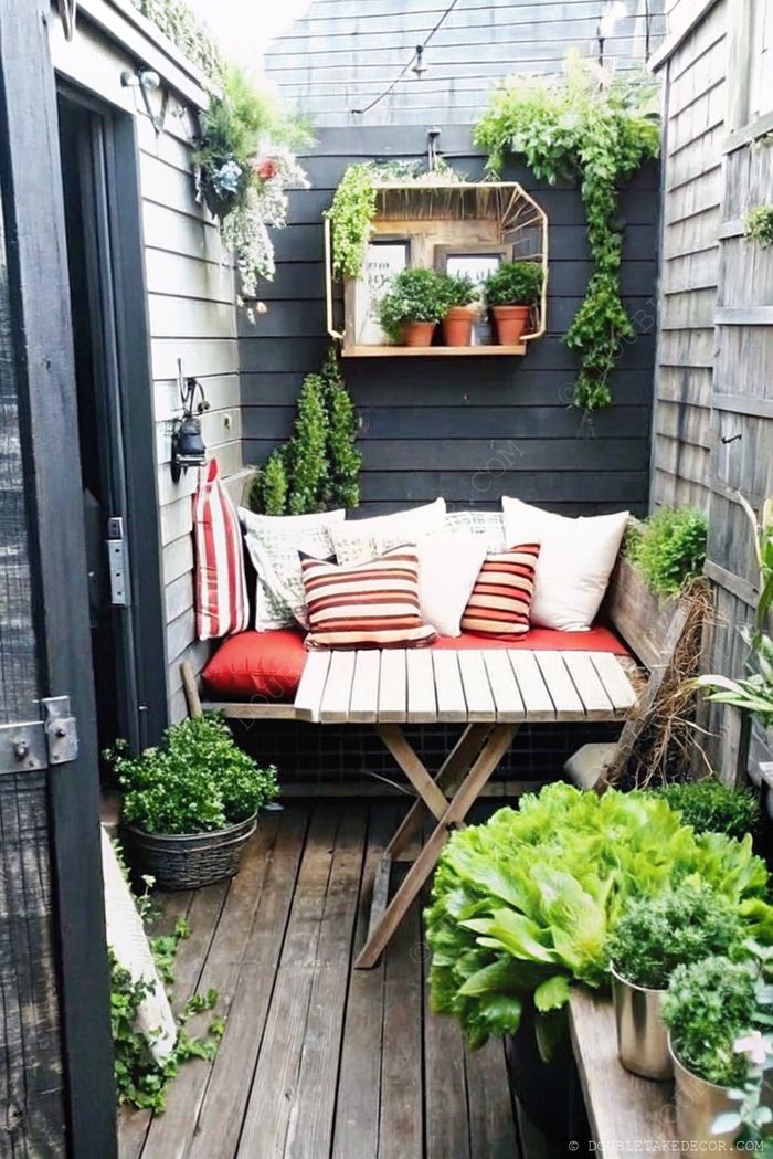 Petit coin cosy à l’extérieur avec banc en bois, coussins déco, plantes en pots et guirlande lumineuse pour une ambiance apaisante.