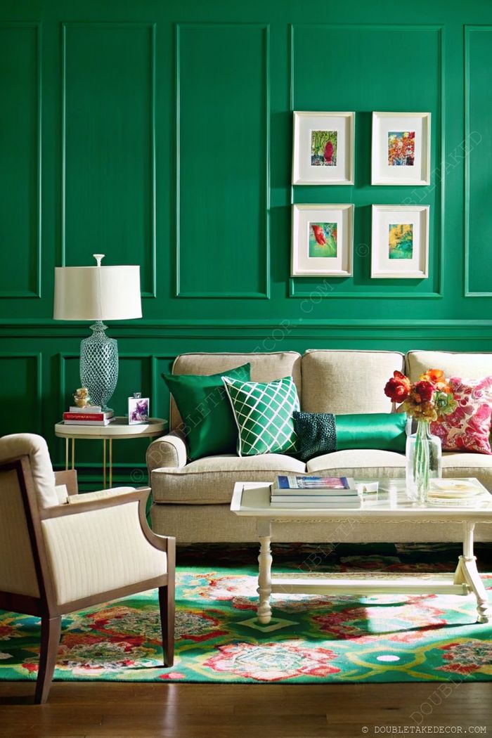 Living room with vibrant green paneled wall, beige sofa with green pillows, white coffee table and decorative accessories.