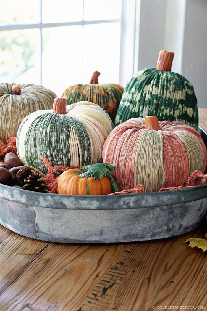 Fall centerpiece with decorative pumpkins in pastel and earthy tones, acorns and pinecones arranged in a metal tray for Halloween table decor.