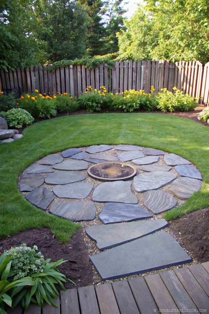 Landscaped circular garden featuring irregular slate stones arranged around a central fire pit area, bordered by lush lawn and yellow flowers.