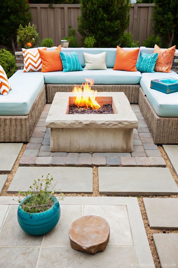 Cozy outdoor living area featuring a blue U-shaped sectional with colorful pillows surrounding a central stone fire pit on a paver stone patio.
