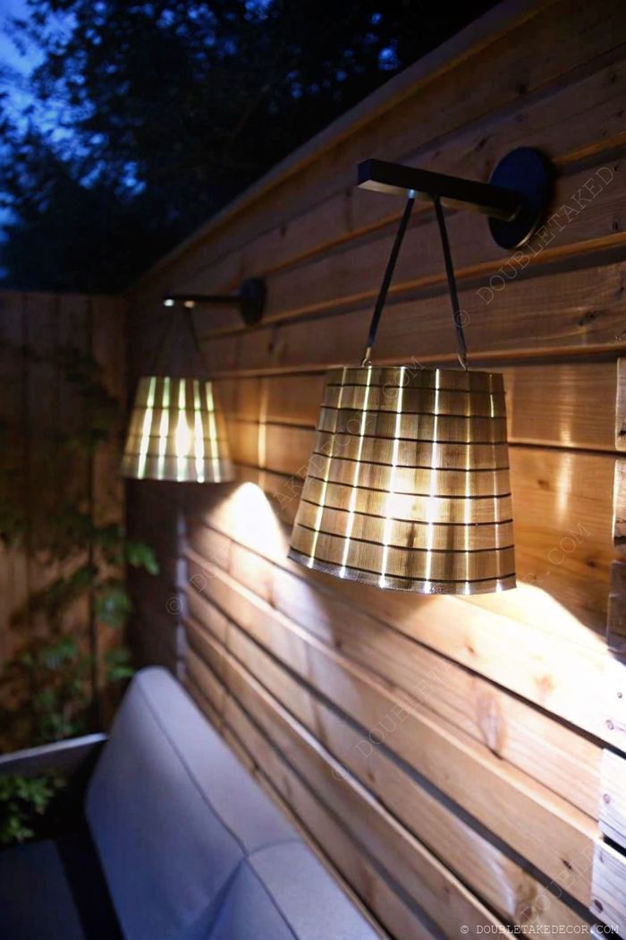 Elegant outdoor space with striped pendant lights hanging above a gray sofa, creating a warm, inviting atmosphere for evening relaxation.