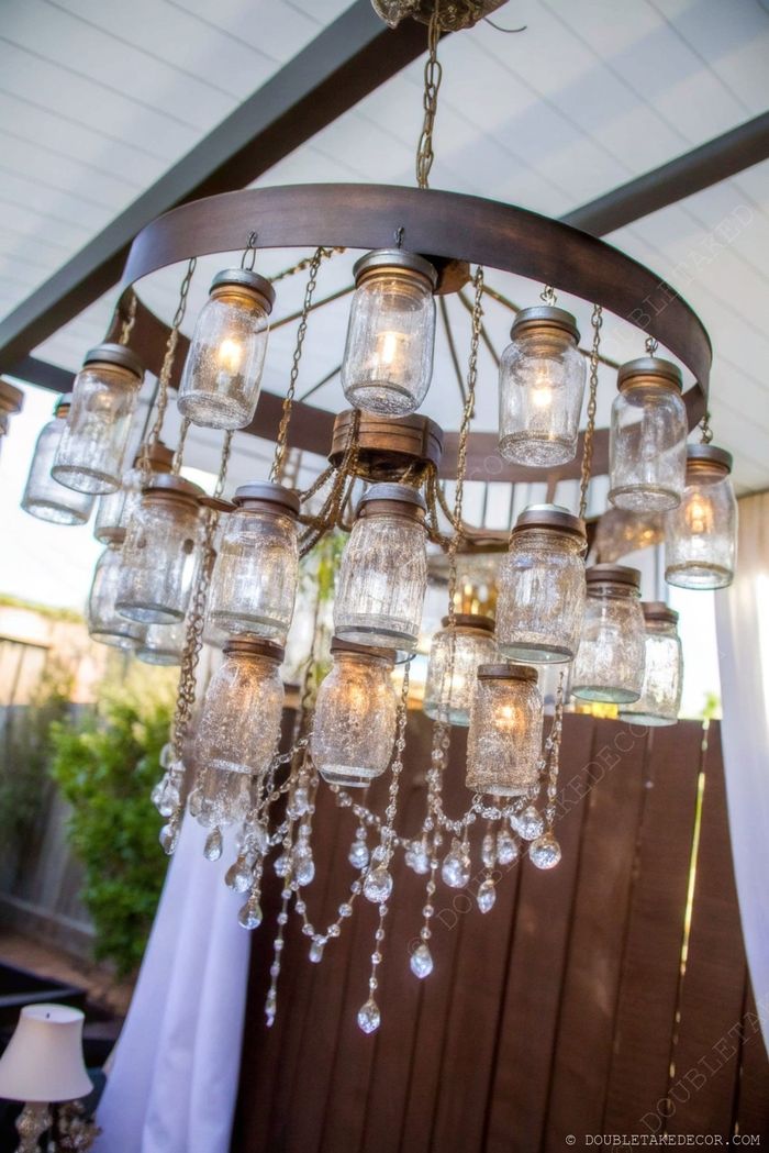 Circular metal chandelier with mason jar light fixtures and hanging crystal beads creating a rustic-elegant outdoor lighting centerpiece