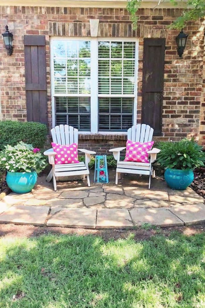Deux fauteuils blancs Adirondack avec coussins à pois roses sur une terrasse en pierre, accentués par des pots turquoise et une lanterne déco.