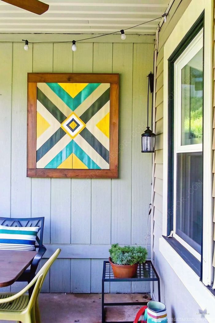 Colorful geometric wall art in teal and yellow creates a focal point on this cozy patio with string lights and yellow accent chair.