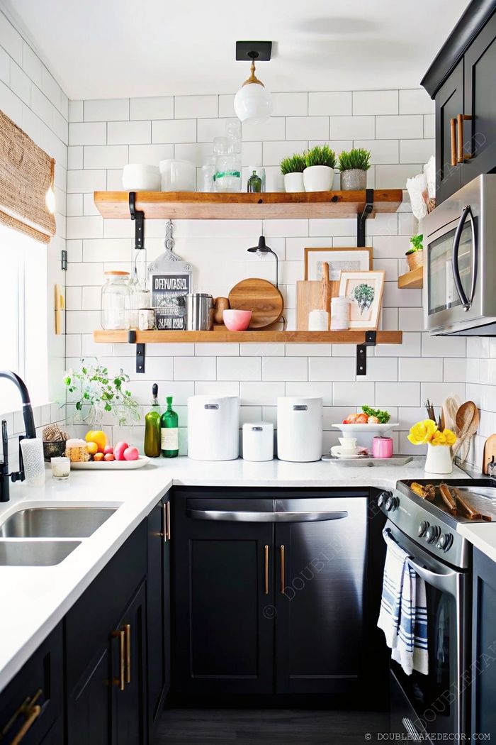 Modern kitchen corner featuring wooden shelves, black cabinets with gold pulls, and stylish decor elements for small spaces.