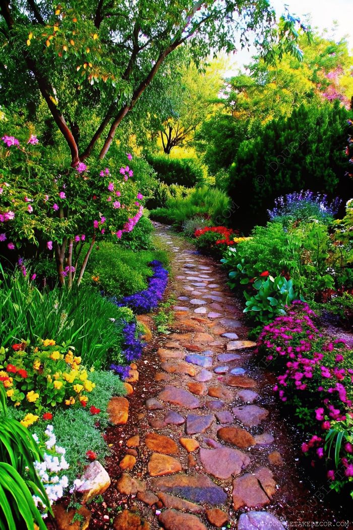Garden pathway with irregular stone slabs winding through colorful flowers and lush greenery under dappled sunlight.